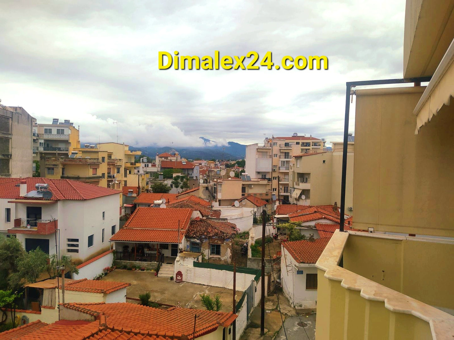 Панорама на жилищна зона в Комотини, Гърция с червени покриви и облачно небе.