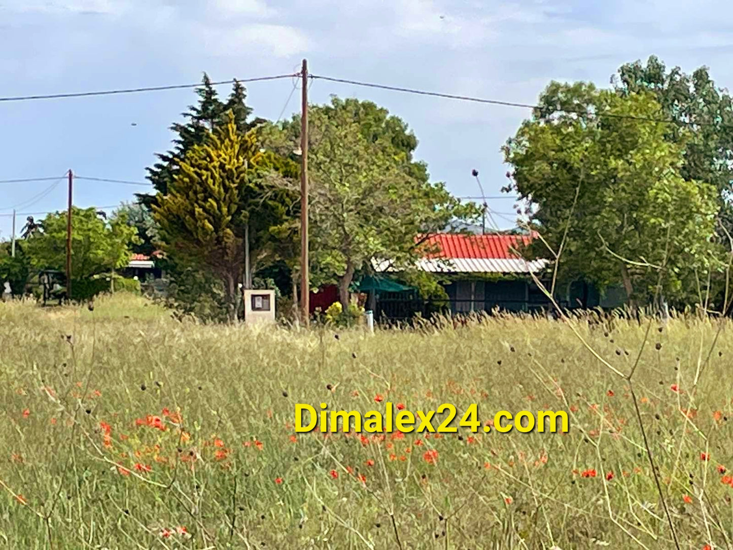 Парцел в Крионери, Гърция, със зелена поляна и видими къщи на фона, близо до морето.