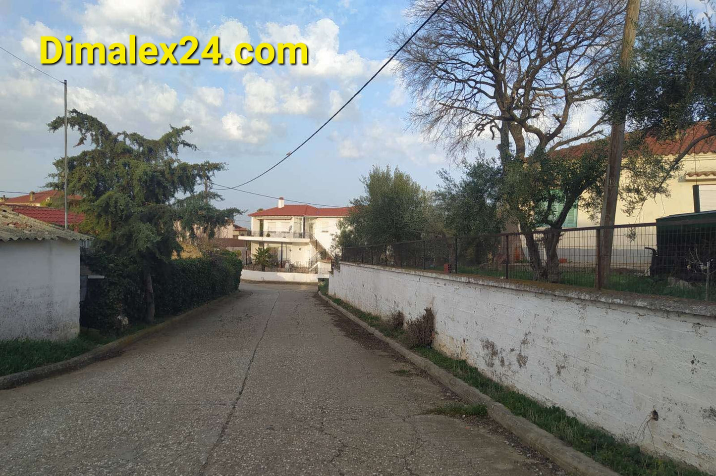 Улица в село Ксилагани, Гърция, заобиколена от зеленина и къщи, идеална за недвижими имоти в Гърция.