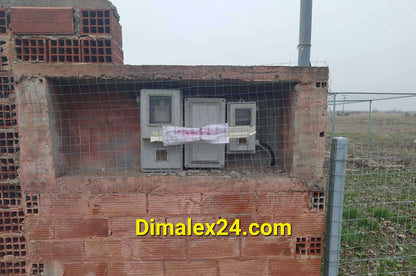 Electric meter installation on a brick wall in a rural area, showcasing utility setup.