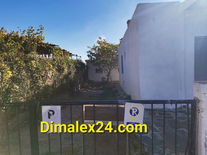 Entrance to a property in Makri, Greece with a garden and fencing, showcasing available real estate.