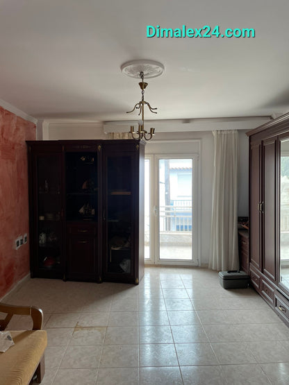 Interior view of a cozy living room featuring a chandelier, shelves, and access to a balcony.