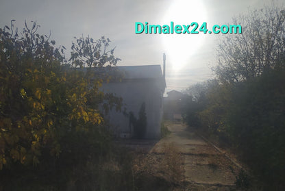 View of a house in Profitis Ilias, Northern Greece, surrounded by greenery and a sunlit path.