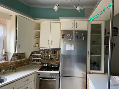 Modern kitchen space with white cabinets, stainless steel appliances, and a cozy dining area in a mezonet in Northern Greece.