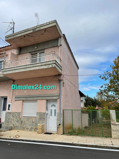 Exterior view of N.22 House in Xilagani, Northern Greece, featuring a pink facade and garden.