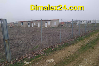 Fenced plot of land with structures in a misty environment, ideal for affordable property investment in Northern Greece.