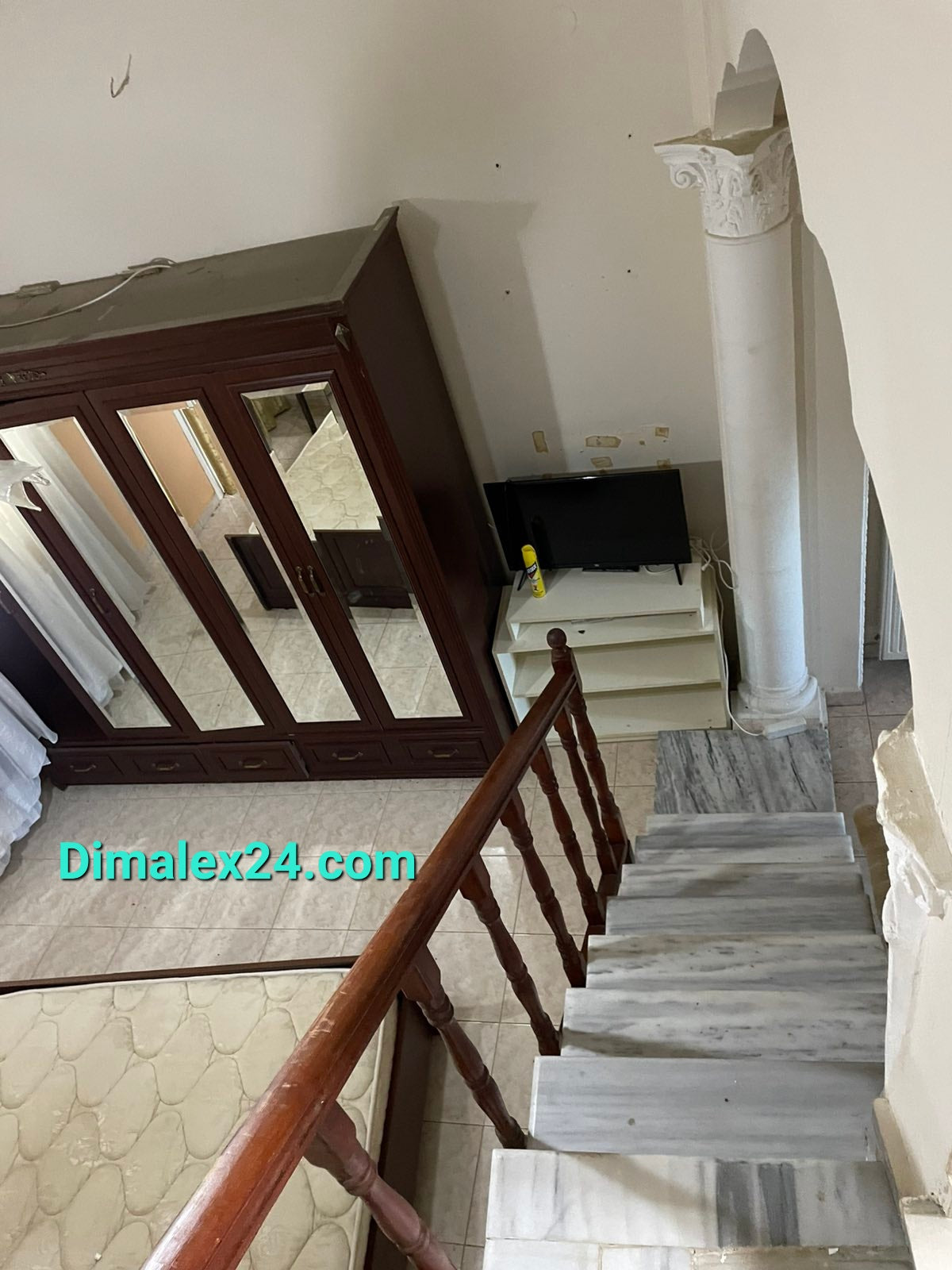 Interior view of a staircase leading to a welcoming living space with wooden furnishings and marble flooring.