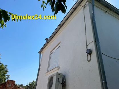 Two-story house in Prosaknites, Northern Greece, highlighting exterior features and air conditioning unit.