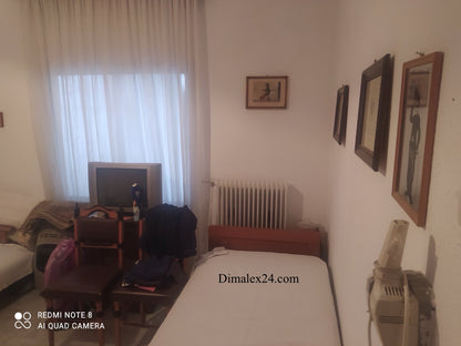 Cozy interior of a bedroom in a house in Ksilagani, featuring a bed, radiator, and framed art.