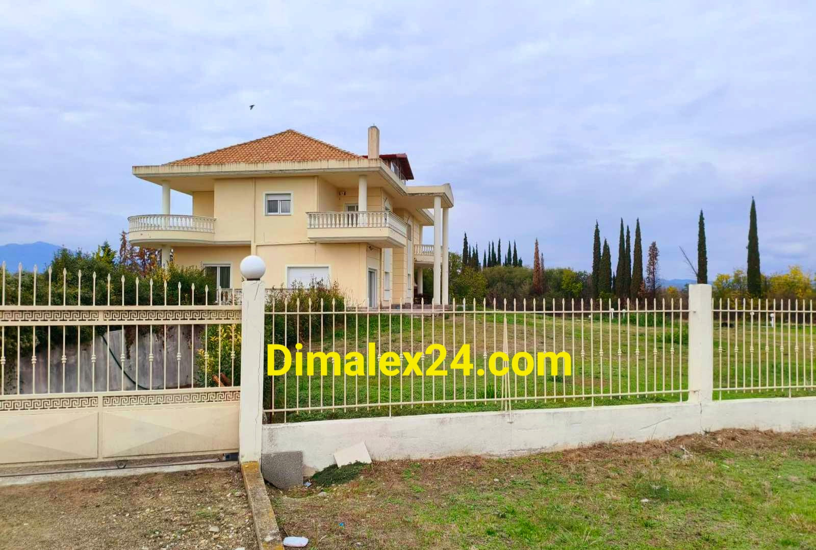 Просторен двор с ограда и порта за кола и двуетажна къща с панорамни тераси с гледка към двора и околностите.