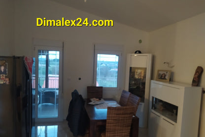 Cozy dining area with a table, wicker chairs, and large windows in a modern home.