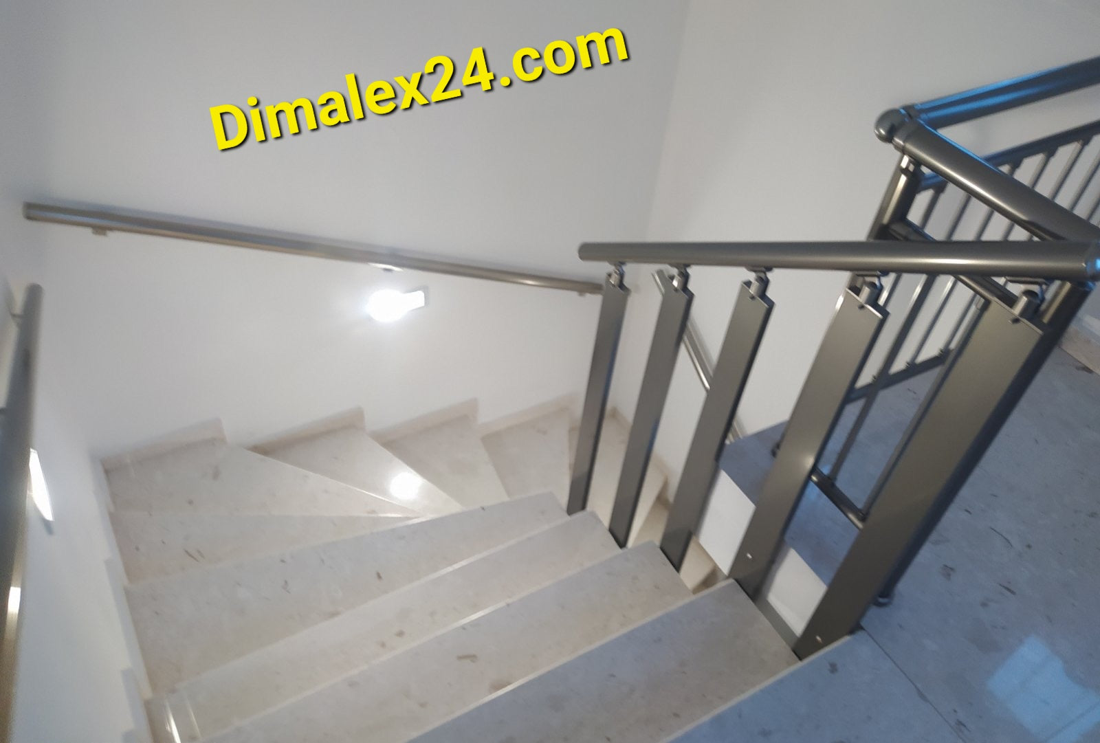 View of a modern staircase with metal railing and marble steps, showcasing elegant interior design.