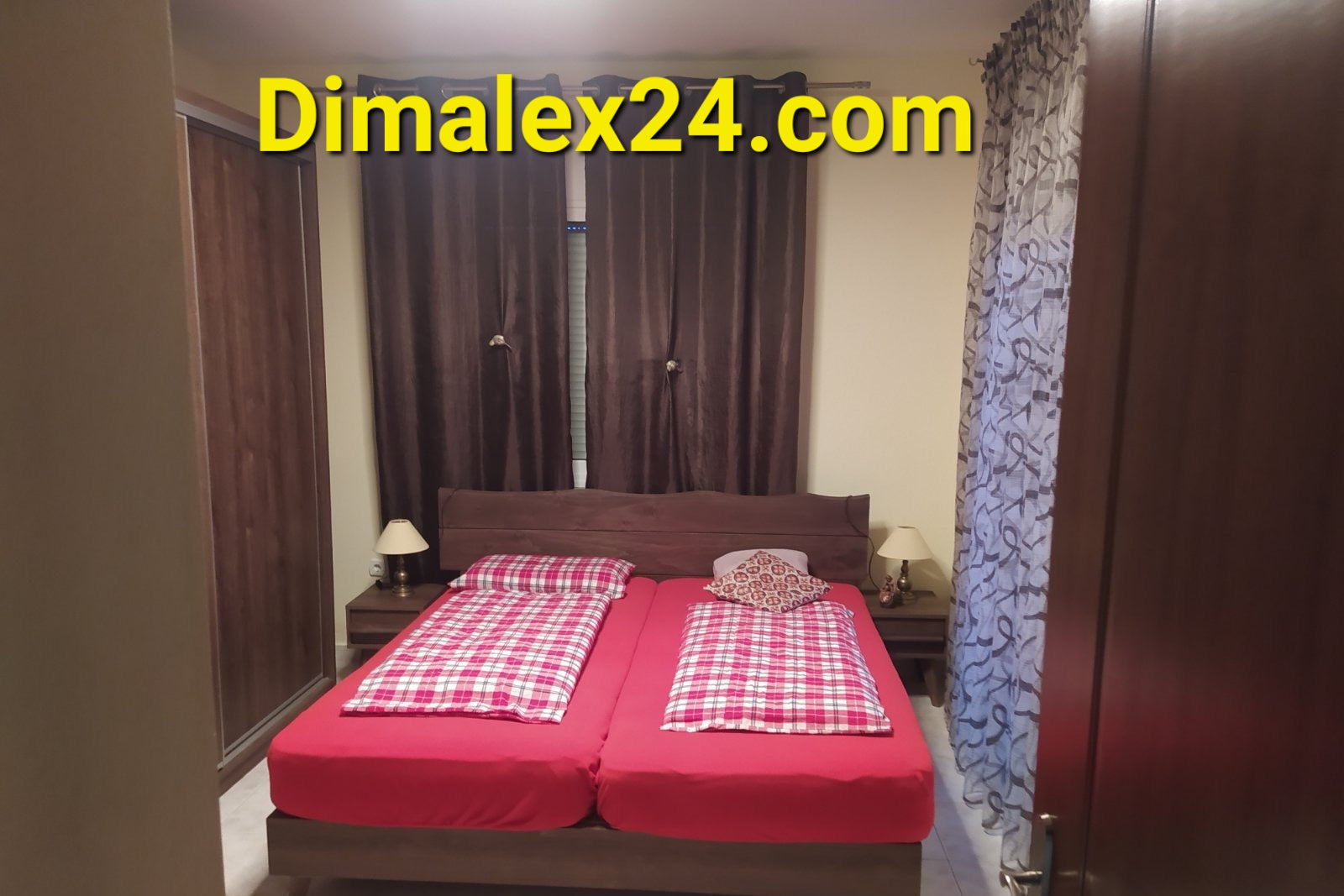 Cozy bedroom with a red checkered bedding set and wooden furniture, featuring curtains and bedside lamps.