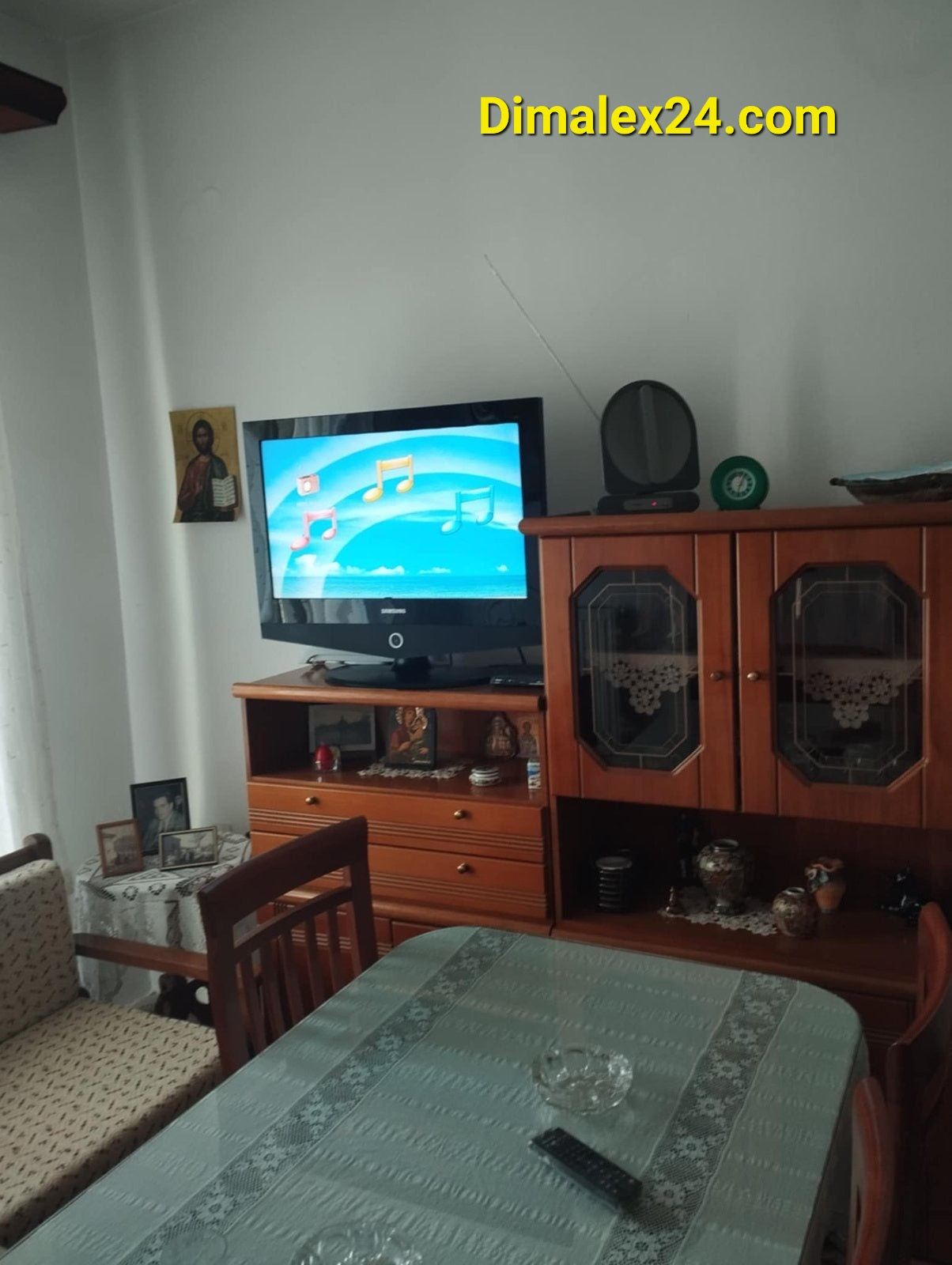 Interior of a cozy living room featuring a TV, wooden furniture, and a dining table.