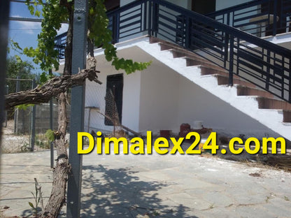 Exterior view of a house in Greece with a staircase and vine plants, ideal for peaceful living.