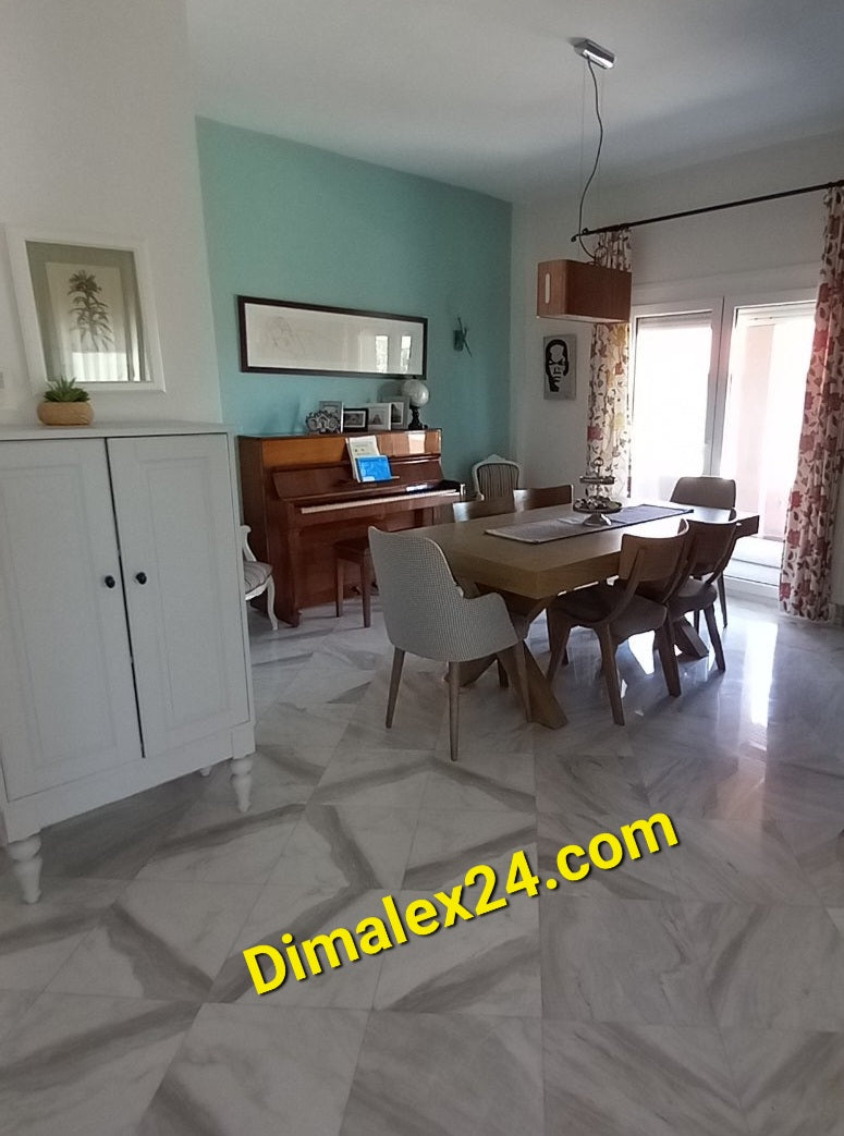 Bright dining room with wooden table and chairs, white cabinet, and piano, showcasing modern interior design.