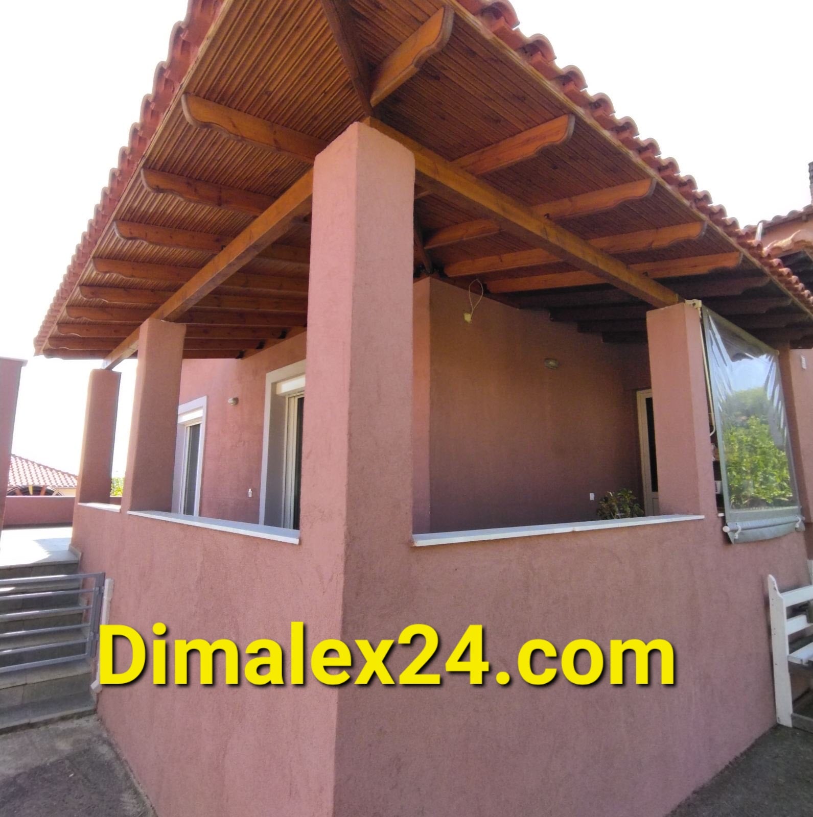 Exterior view of a house in Greece, showcasing its architecture and covered porch.