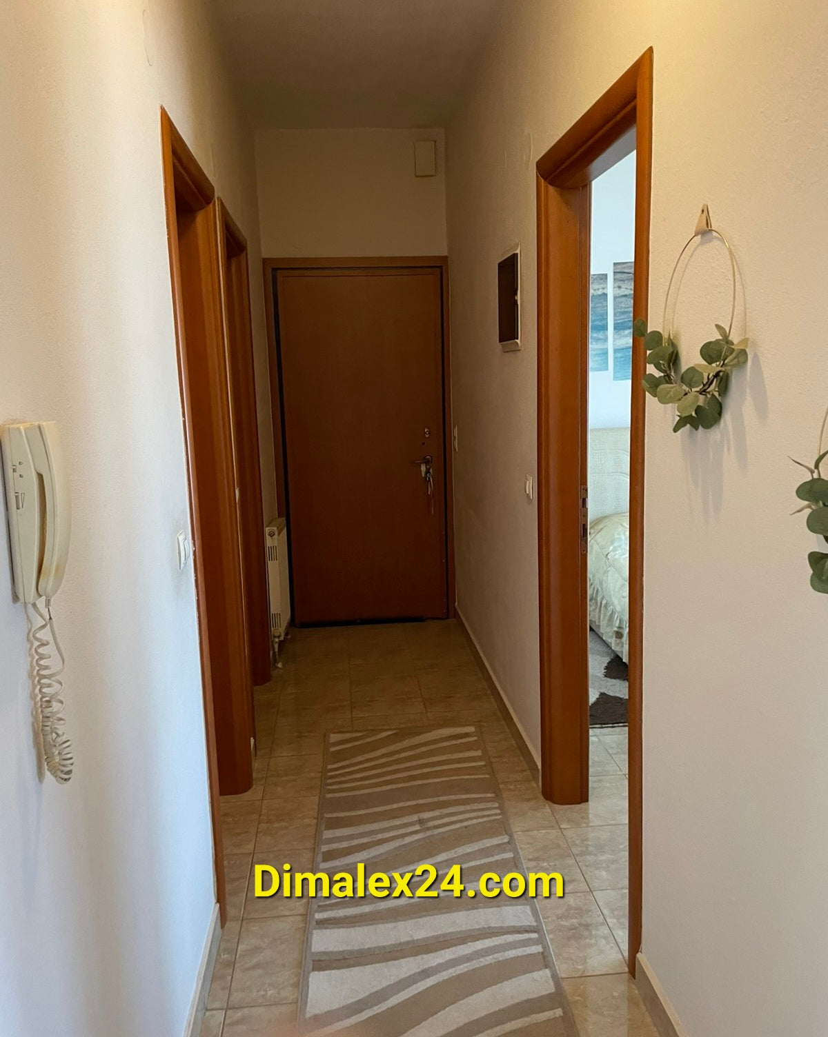Hallway view of a modern apartment in Greece, featuring wooden doors and light-colored walls.