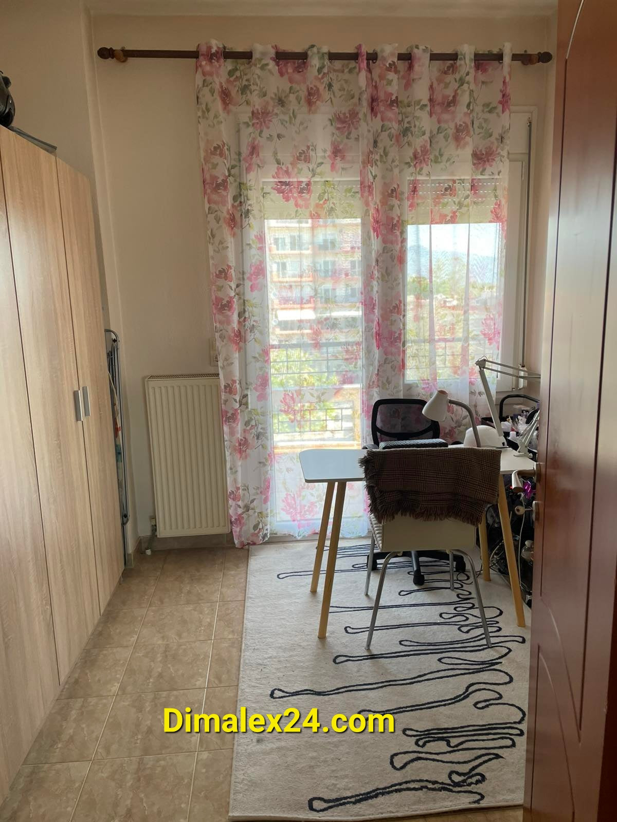 Cozy interior of an apartment in Greece featuring floral curtains and a small dining area.