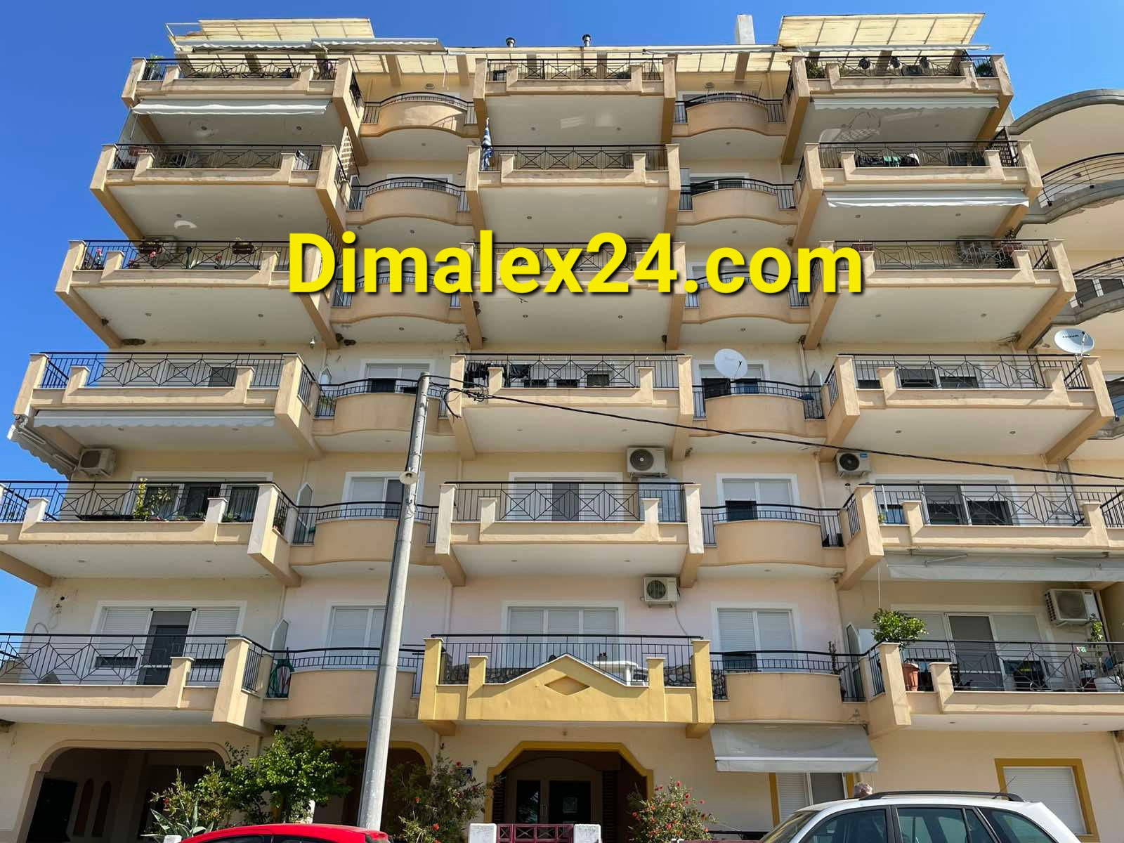 Six-story apartment building in Chrisopoli, Greece, showcasing balconies and modern architecture.