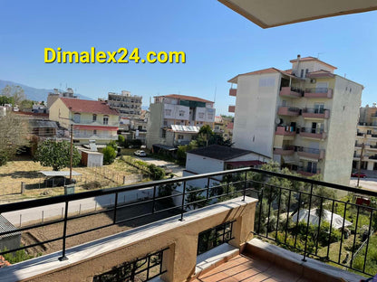 View from the balcony of a 3rd-floor apartment in Chrysoúpolis, Greece, showcasing surrounding buildings and greenery.
