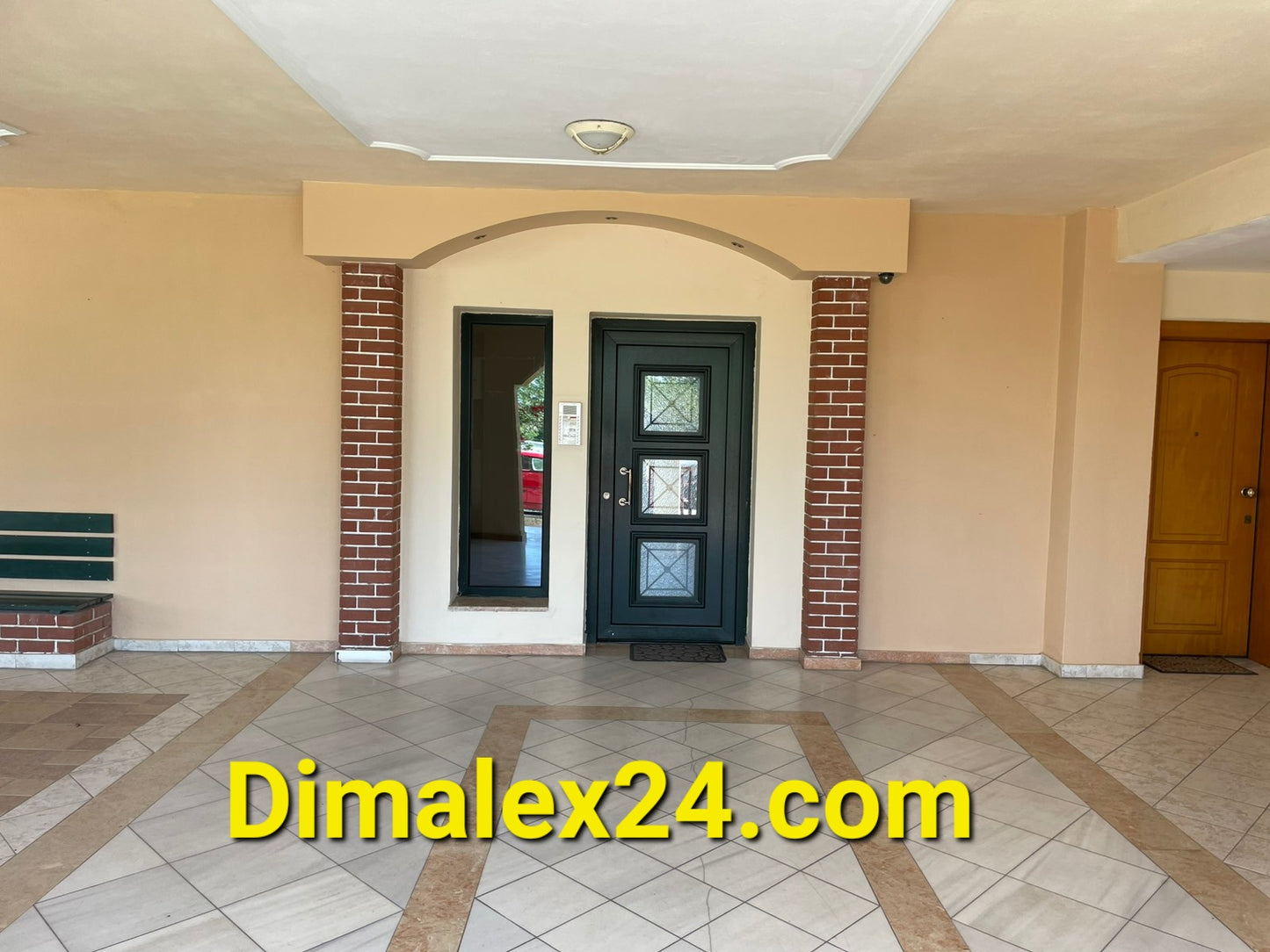 Entrance of an apartment building in Greece featuring a green door and tiled flooring.
