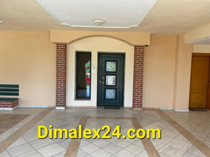 Entrance of an apartment building in Greece featuring a green door and tiled flooring.