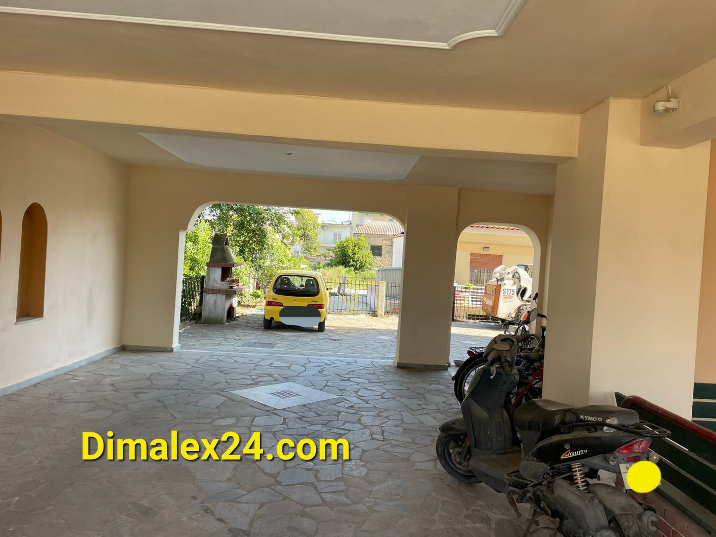 Interior view of parking area in an apartment building in Greece with vehicles and stone floor.