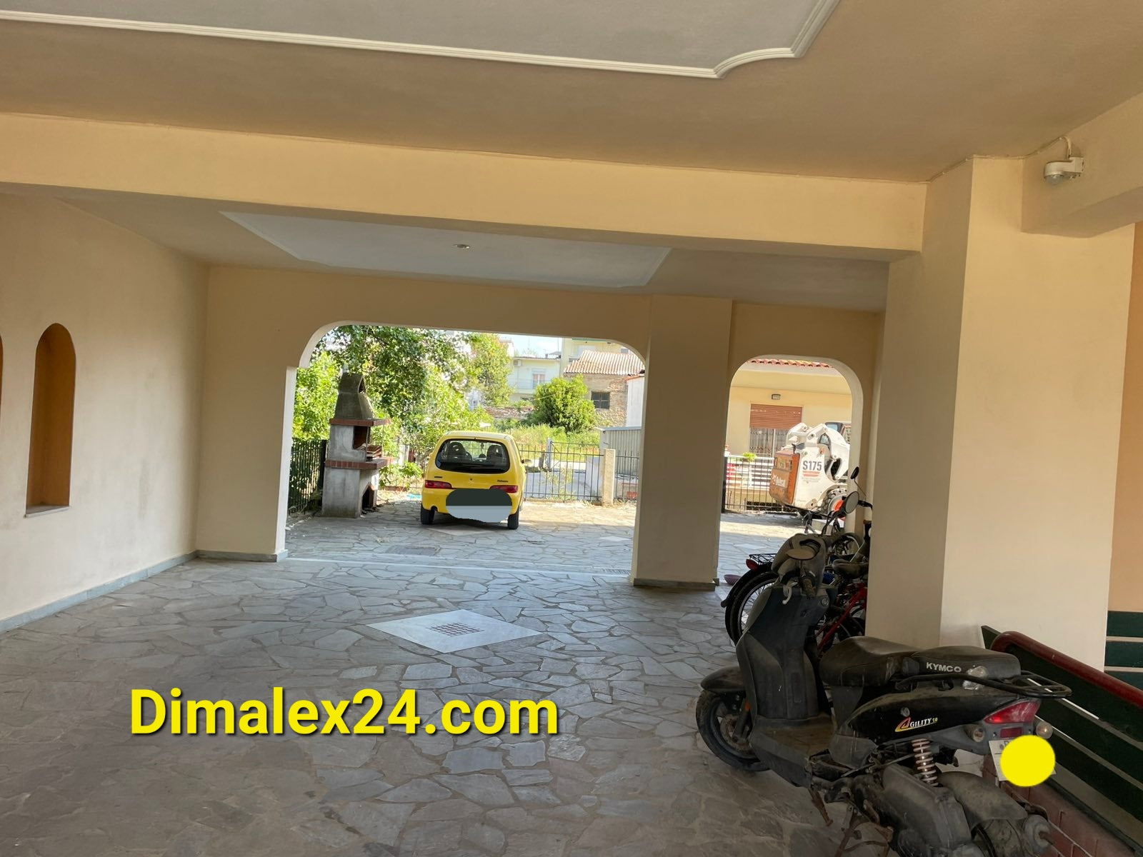 Interior view of parking area in an apartment building in Greece with vehicles and stone floor.