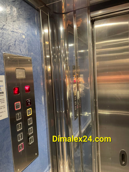 Interior view of an elevator with control panel and mirrored walls, showcasing modern design and functionality.