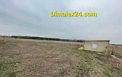 View of a spacious land plot with a small building in the foreground, ideal for investment in Northern Greece.